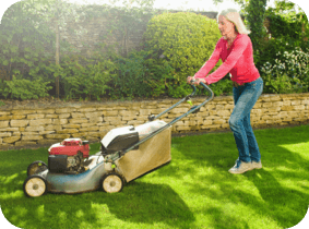 A woman mowing her lawn on a beautiful day 